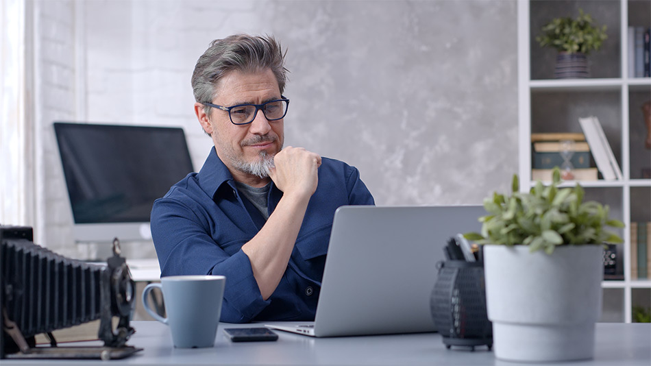 Is-LASIK-worth-it-over-40-Daemon-McClunan-Atlantic-Eye-Laser-Centre-Cape-Town Older man sat at laptop wondering "Is LASIK worth it over 40?"